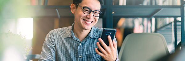 笑みを浮かべながらAndroidデバイスを持って見る男性。