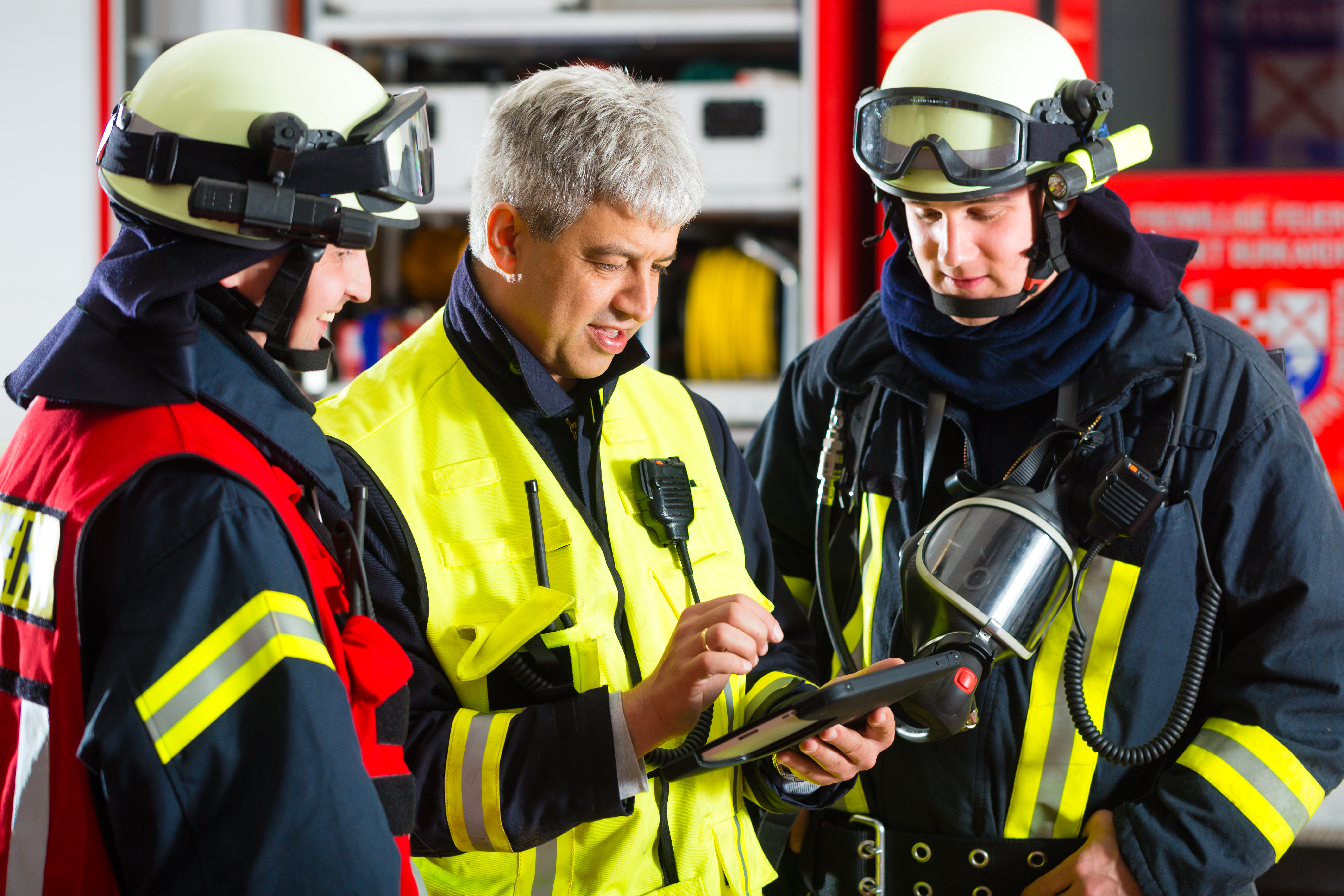 Firefighters looking at a tablet that is managed and secured with the SOTI ONE Platform